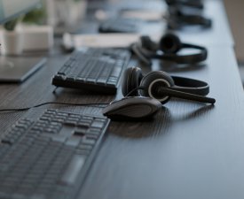 Call center desk with audio headsets and computers, technology used for sutomer care service job. Telemarketing concept at telework office with headphones and monitors. Close up.