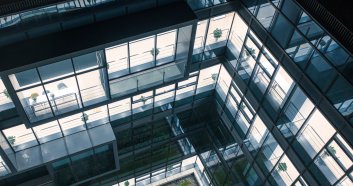 The courtyard garden of a high-tech company has a curved passage surrounded by transparent glass walls.